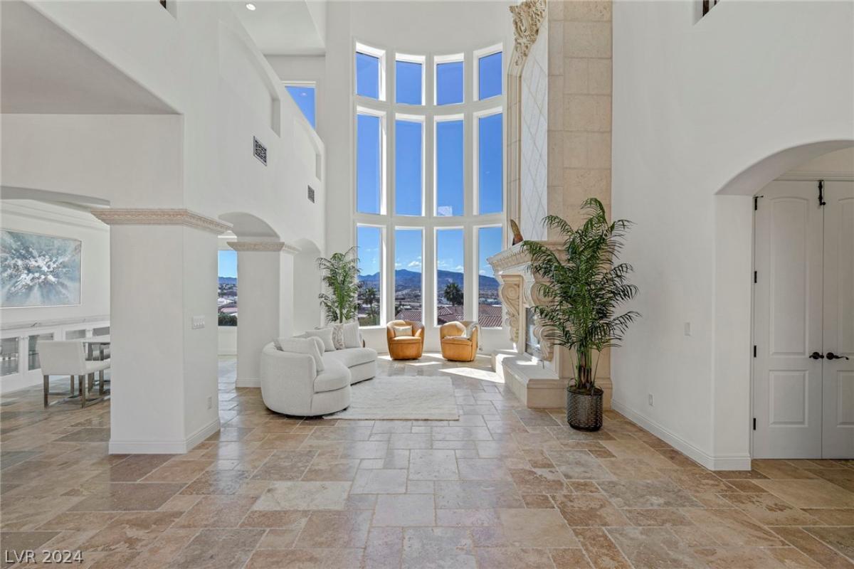 Living room with chairs, sofa and high ceilings.