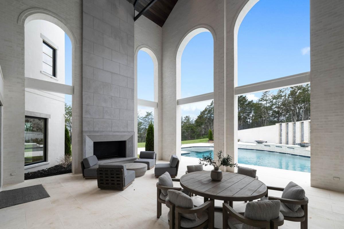 Covered patio with tables, chairs and a fireplace.