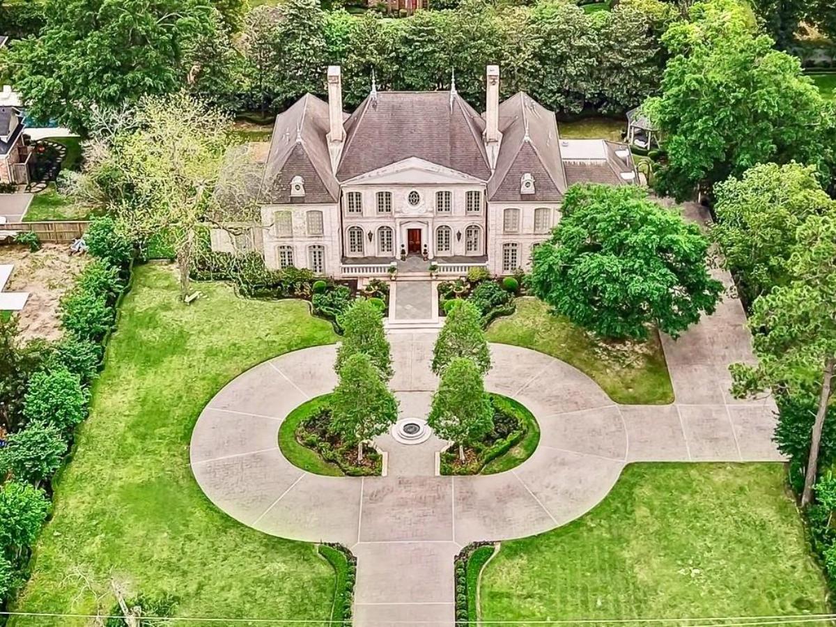 Aerial view of the mansion with a large green lawn.