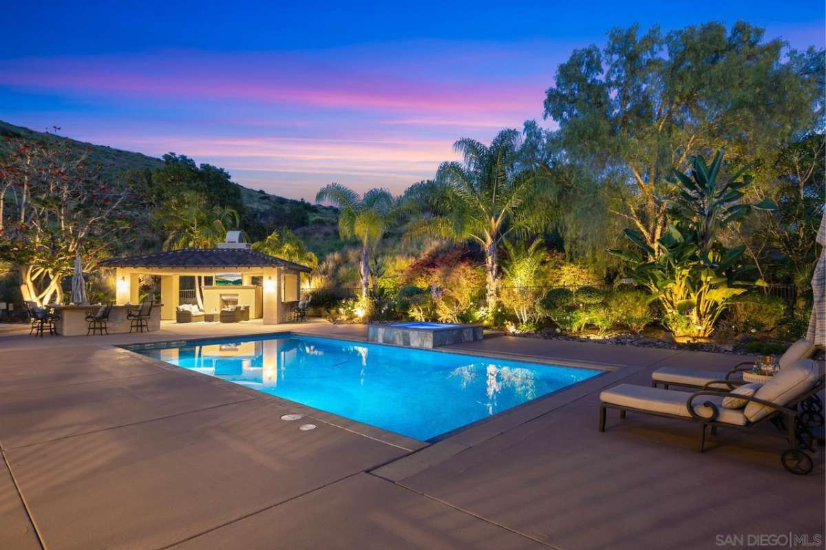 A swimming pool with a jacuzzi and chairs at the poolside.