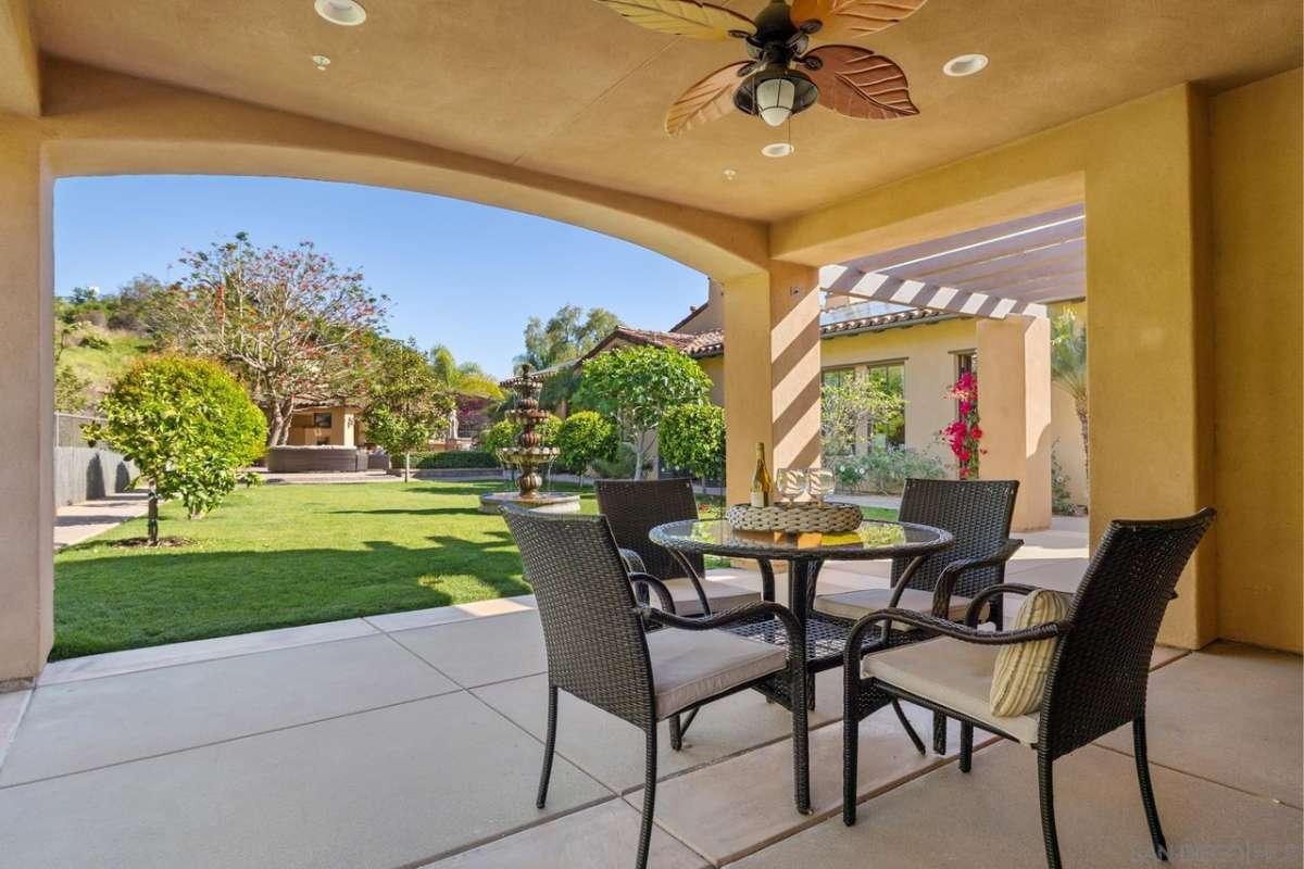A covered patio with a coffee table surrounded by chairs.