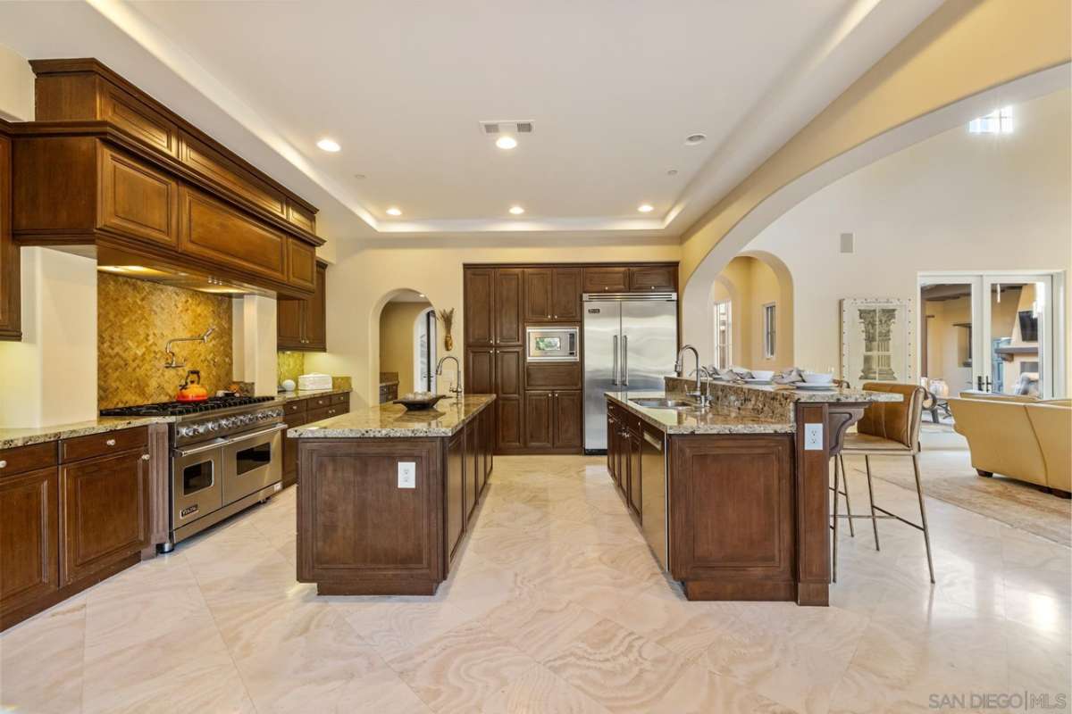 A kitchen with dual islands, countertops, sink, wooden cabinets, and kitchen appliances.