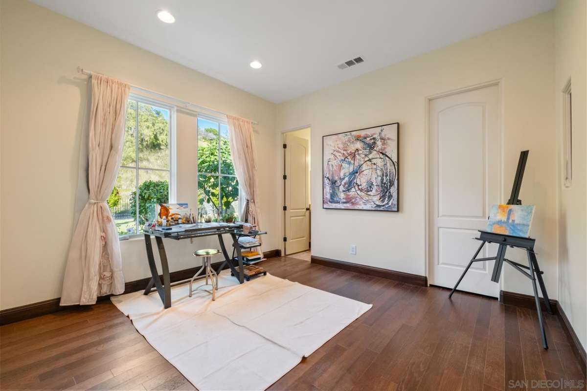 A workroom with a table, chairs, window, and painting.