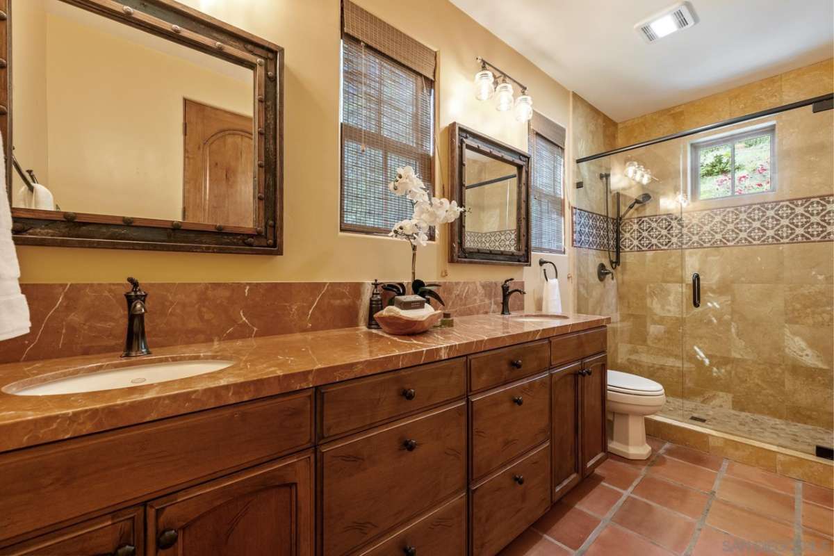 A bathroom with a long vanity, mirror, toilet, and glass shower room.