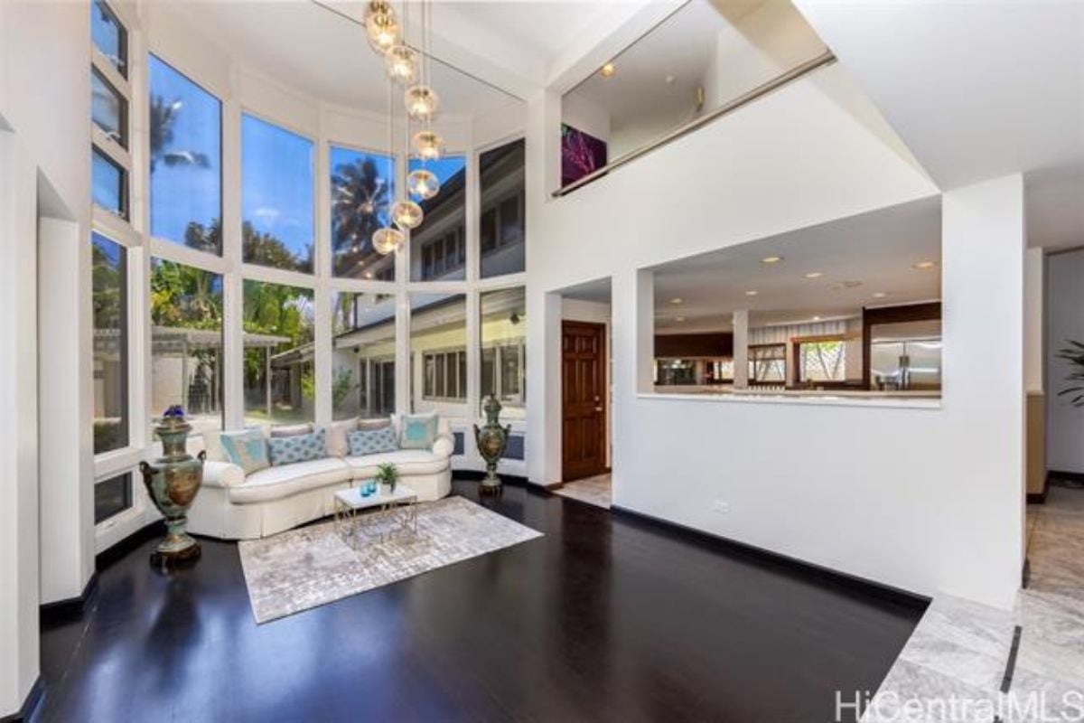A living room with hardwood floors, a white couch, and windows.