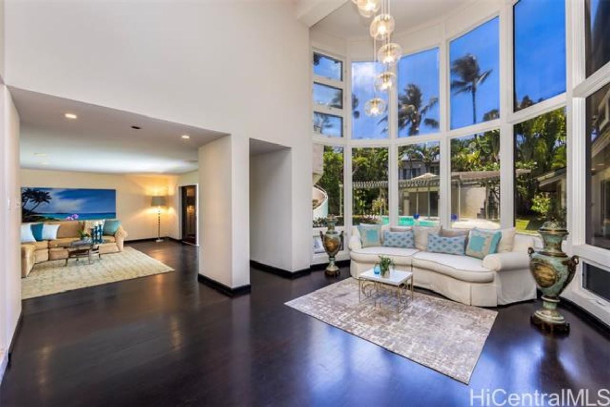 A living room with hardwood floors, a white couch, and windows.