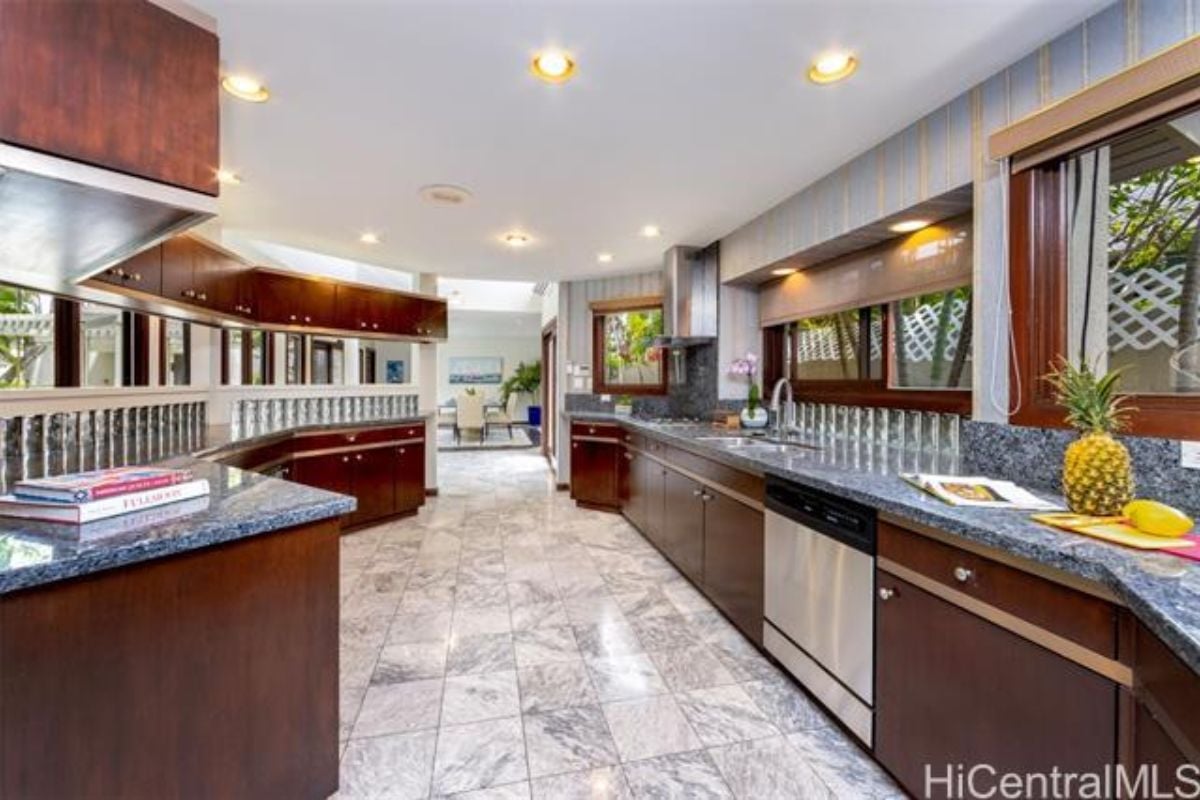 A kitchen with a tiled floor, countertops, sink, kitchen appliances, and cabinets.