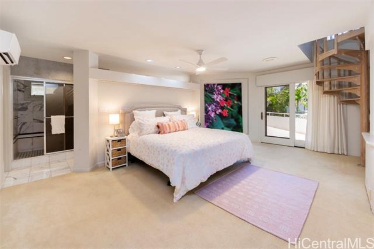 A bedroom with a bed, ceiling fan, painting, window, and nightstand.