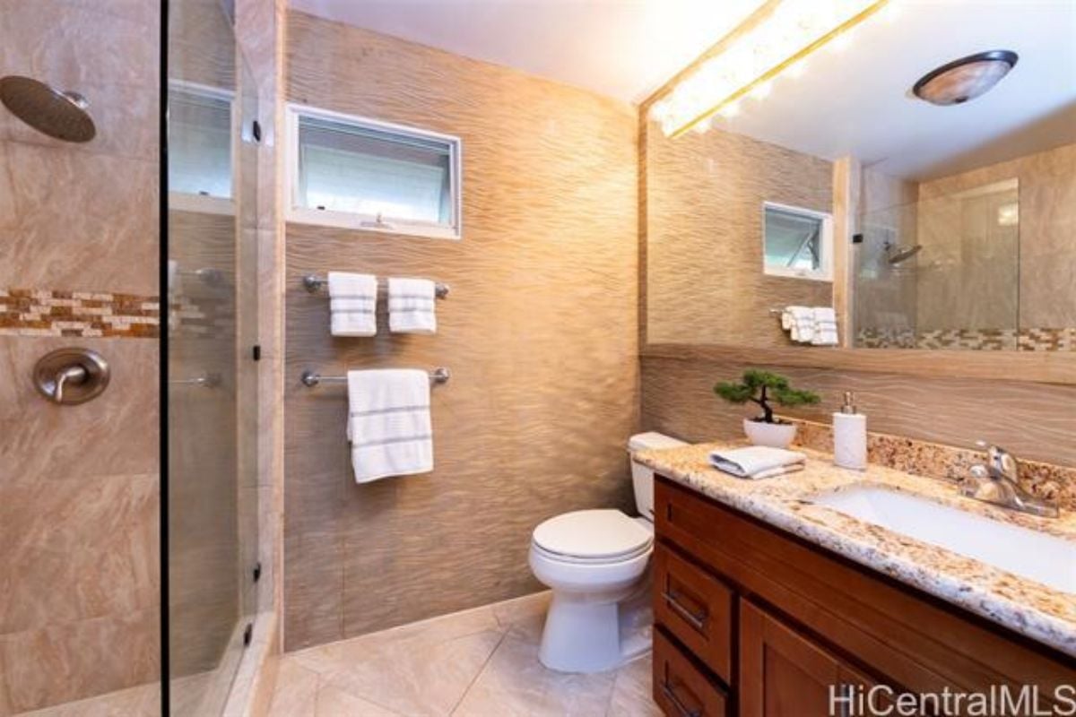 A bathroom with a countertop, sink, mirror, cabinet, and toilet.