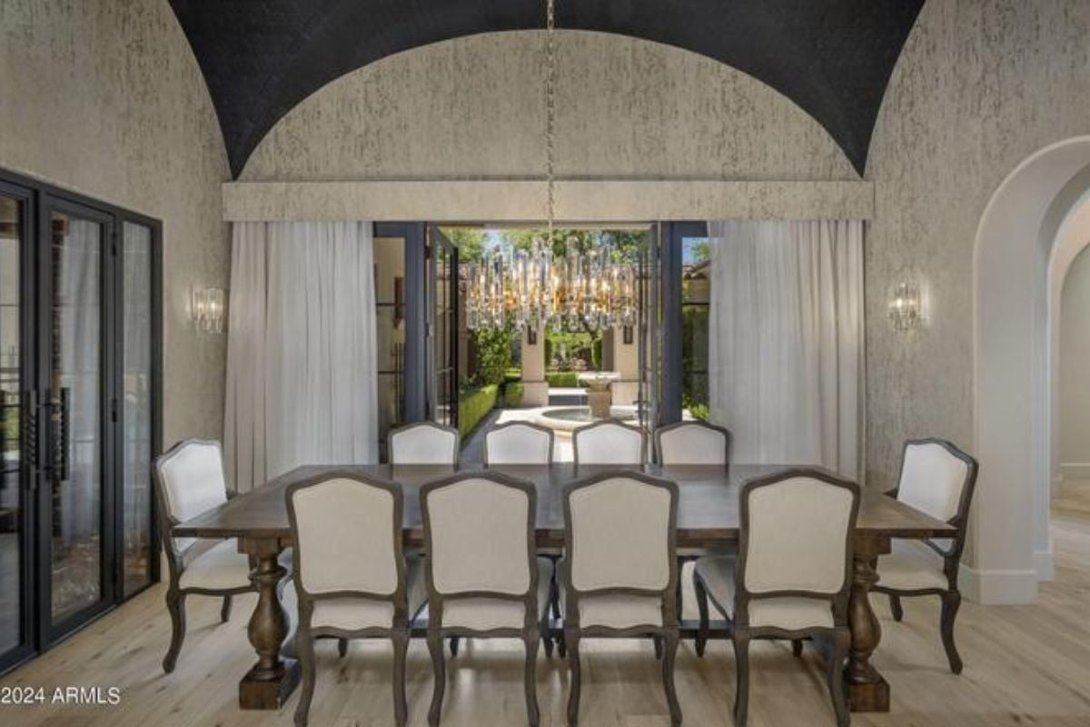 A dining room with a table surrounded by chairs.