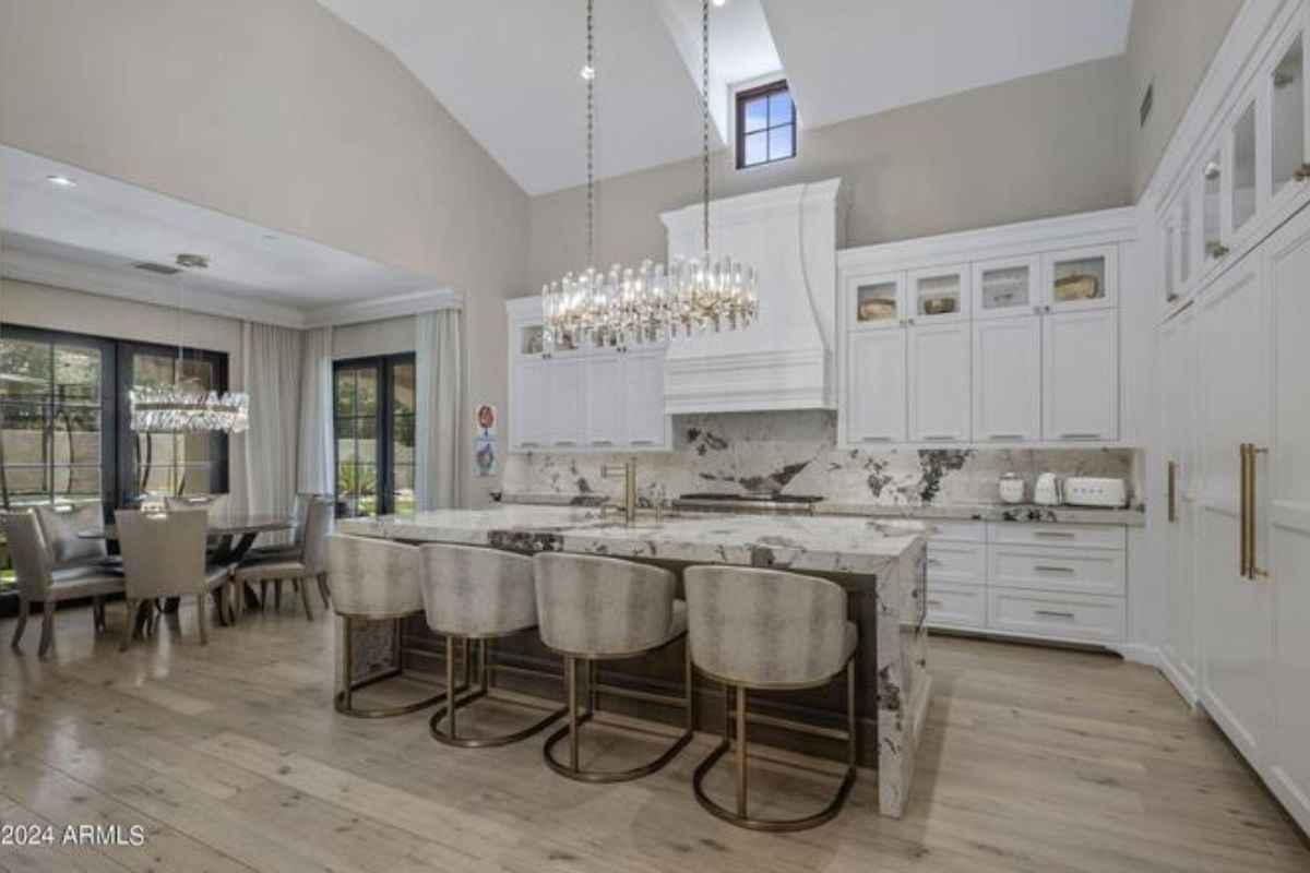 A kitchen with an island, chairs, countertop, and cabinets.