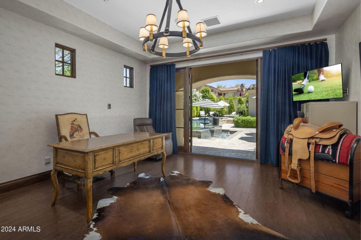A home office with a desk, chest, TV, and chairs.