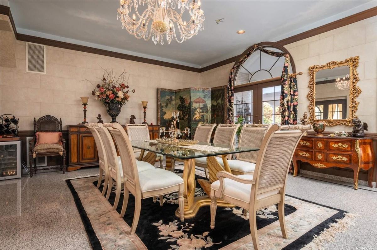 Dining room with a chandelier, glass table and tile flooring.