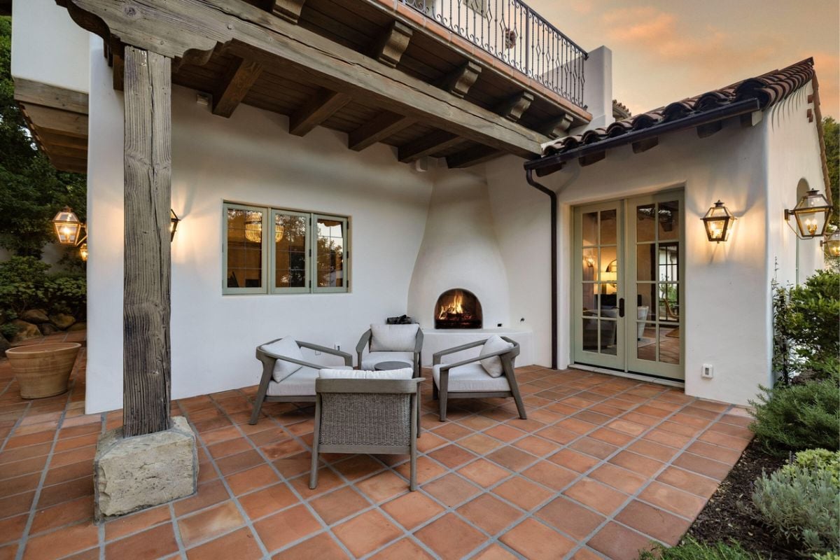 A porch with a fireplace and chairs.