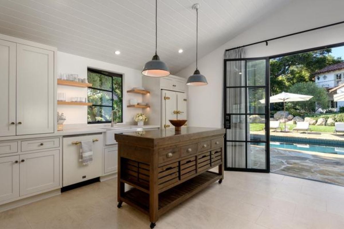 A kitchen with an island, a countertop, white cabinets, a sink, and a window.