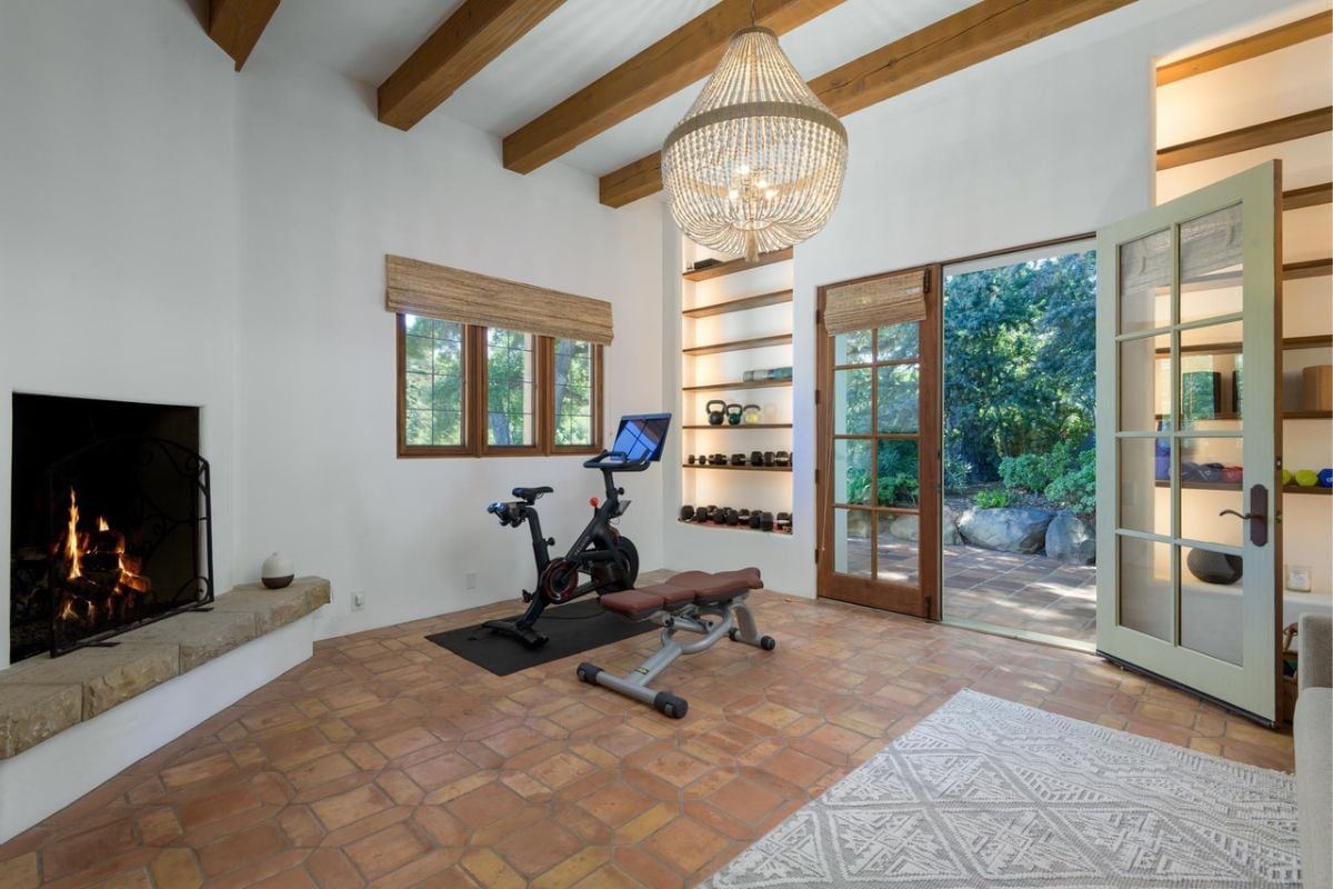 A home gym with an exposed beam ceiling, a fireplace, and gym equipment.