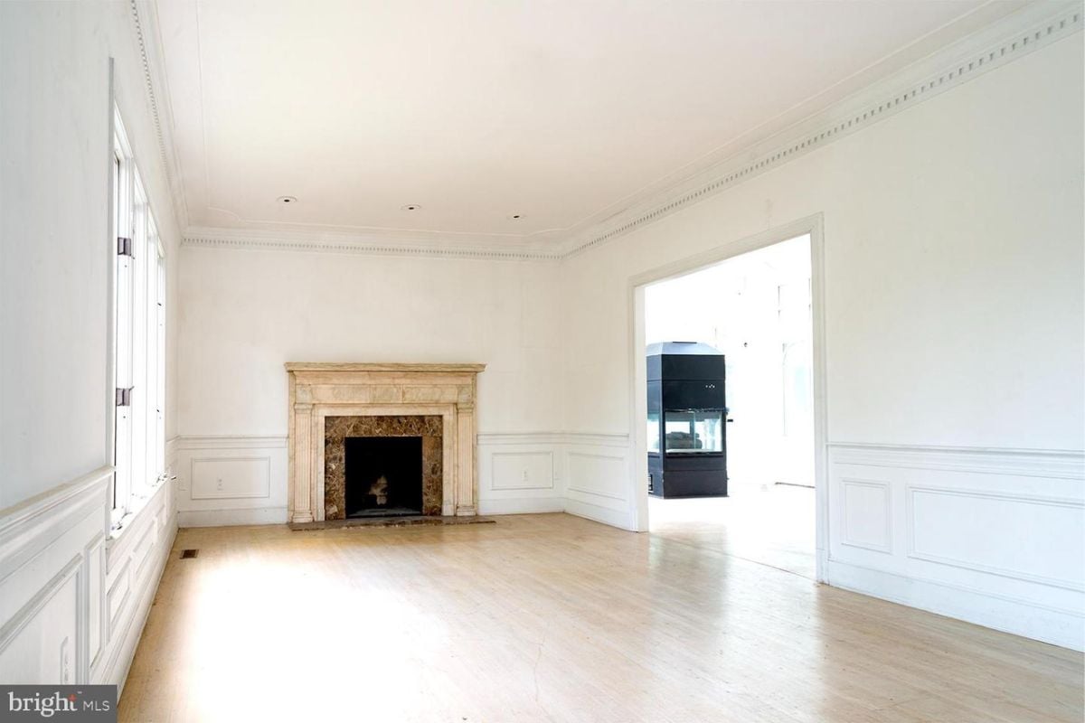 A living room with a fireplace, windows, and wooden floor.