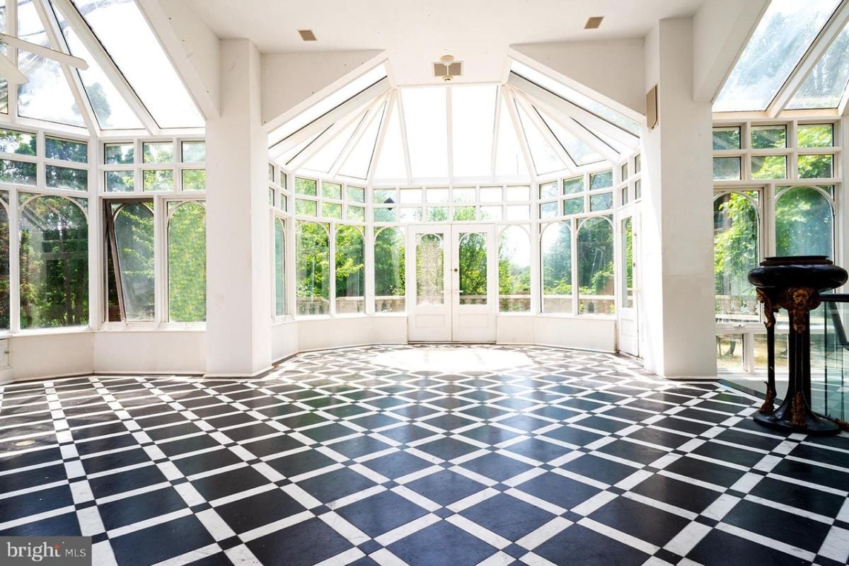 A sunroom with a tiled floor surrounded by windows.