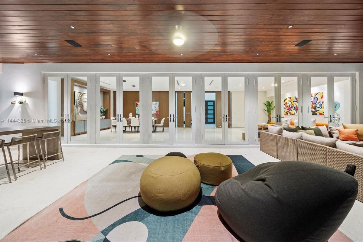A living room with a rug, bean bag chairs, and a wooden ceiling.