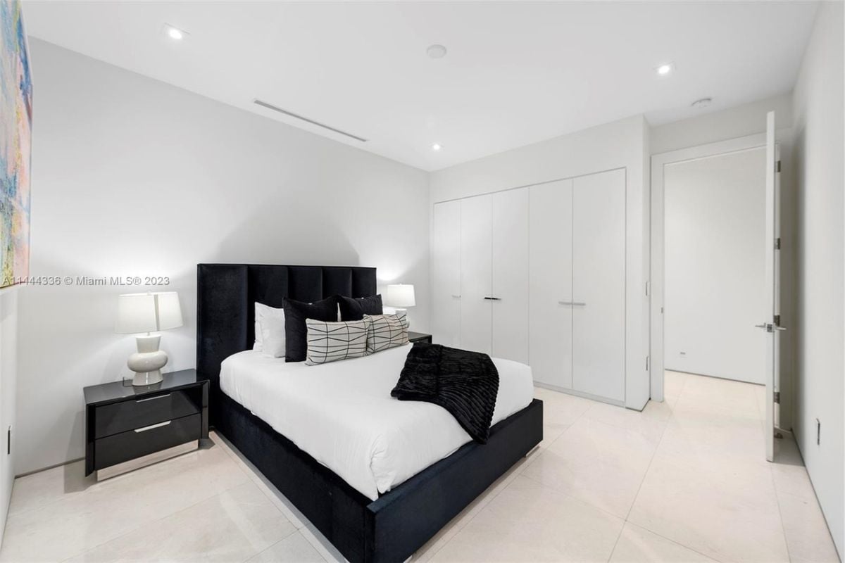 A bedroom with a bed, nightstand, lampshade, and white ceiling.