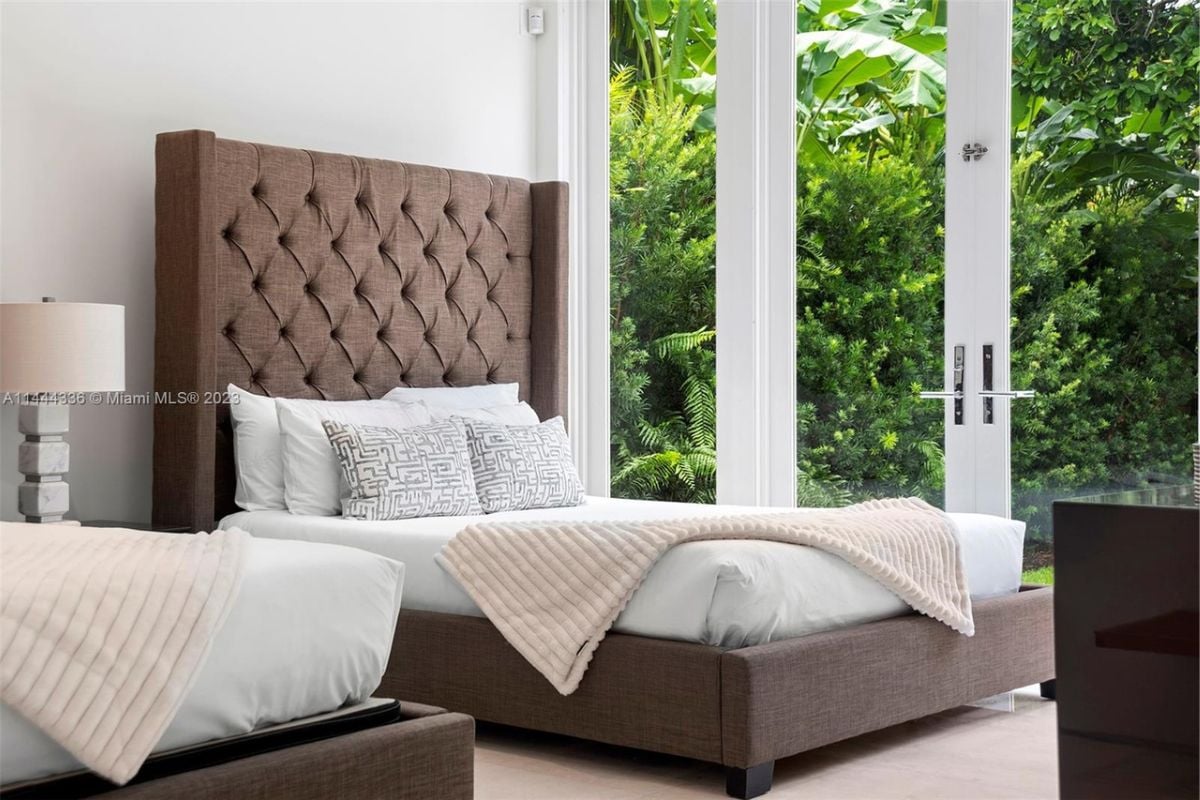 A bedroom with a bed, headboard, nightstand, and lampshade.