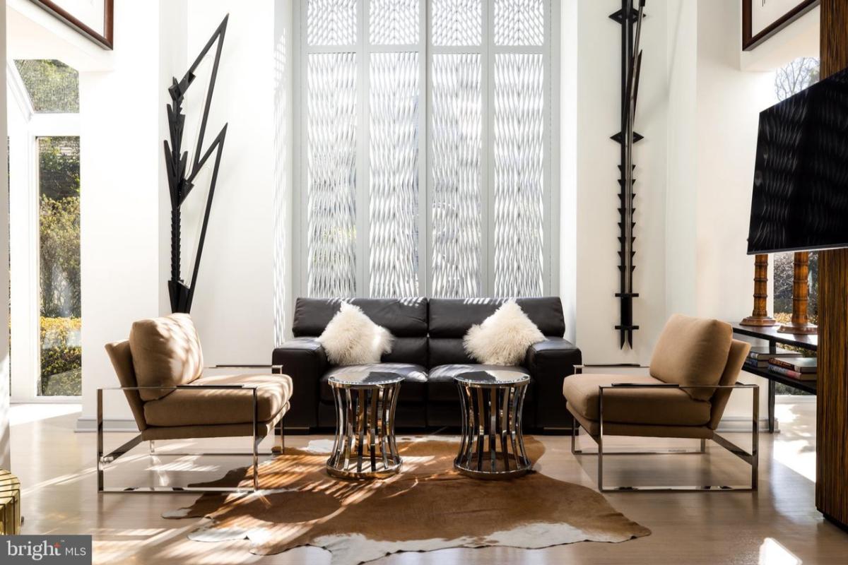 Living room with chairs, couches and a TV.