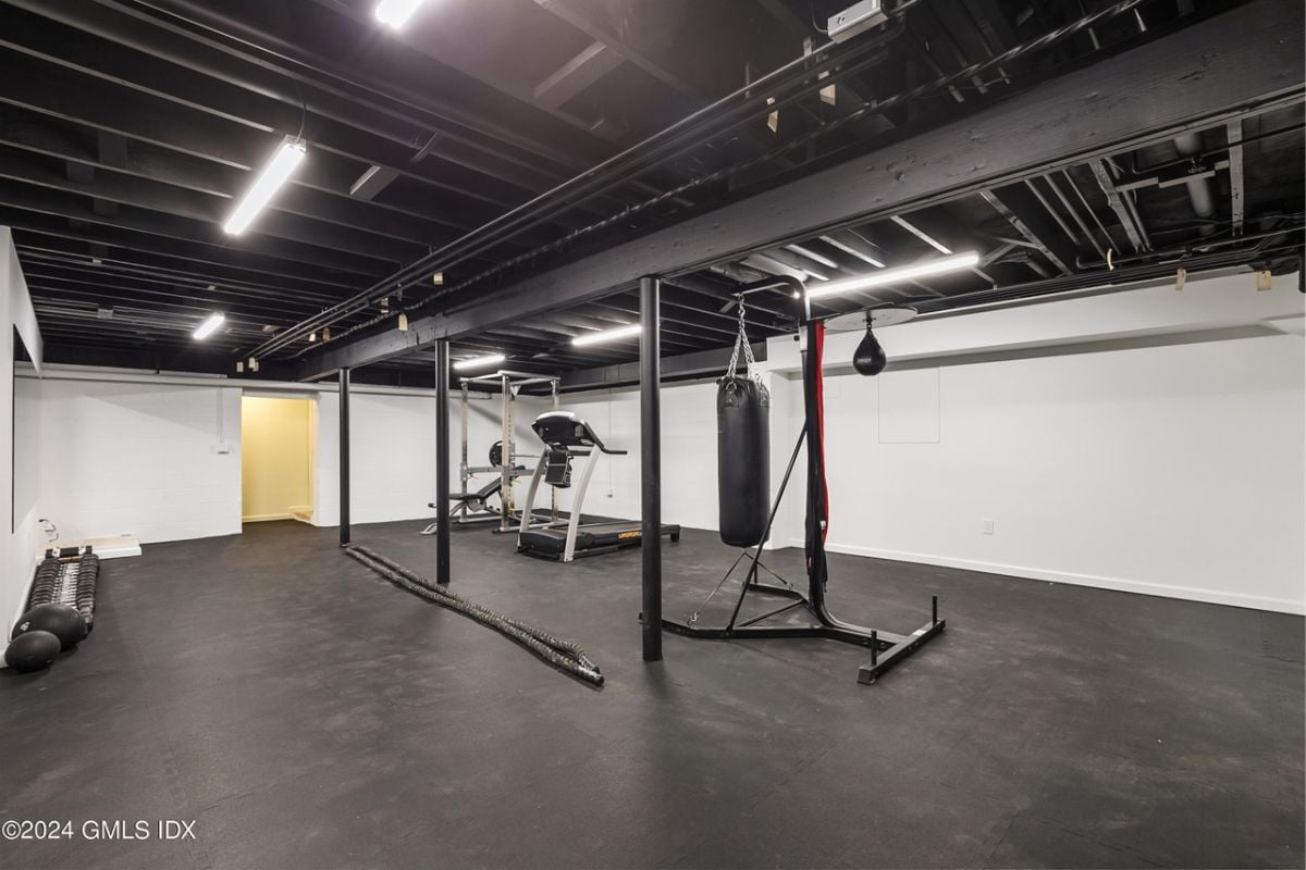 A home gym with an exposed beam ceiling, black floor, and gym equipment.