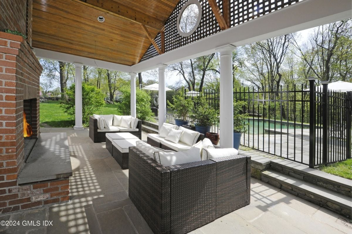 A porch with a fireplace, couches, and a center table.