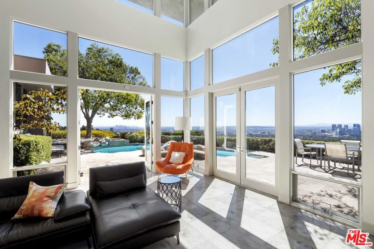 A living room with black couches, windows, and a chair.