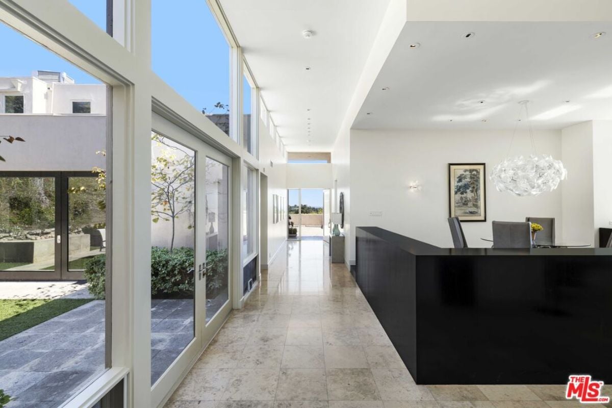 A hallway with a tiled floor, glass walls, and a white ceiling.