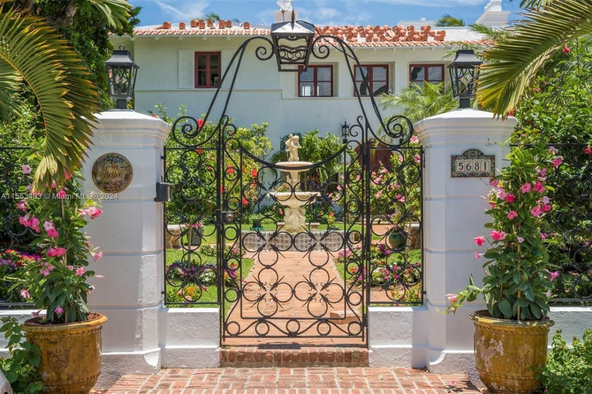 A front gate entry surrounded by plants and trees.