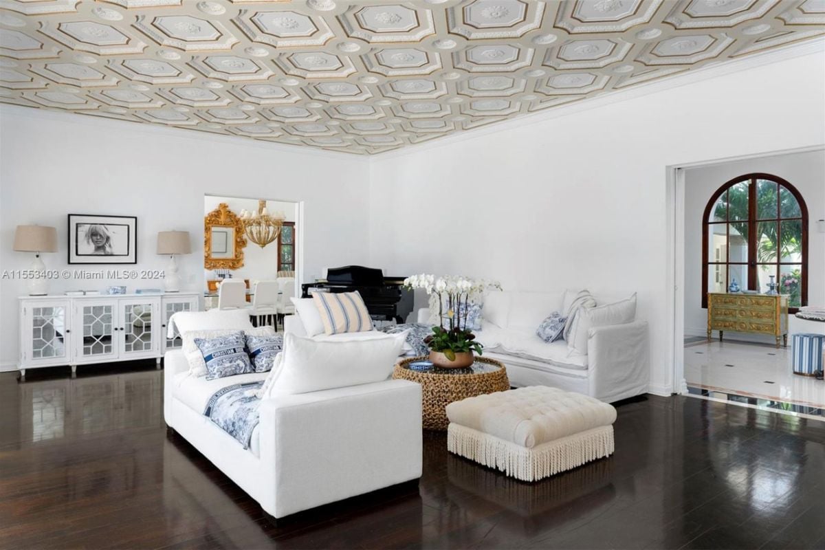 A living room with hardwood floors, ceiling molding, cabinets, couches, and a center table.