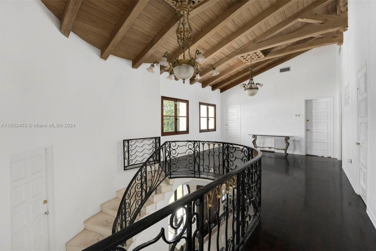 A landing with windows, hardwood floors, and an exposed beam ceiling.