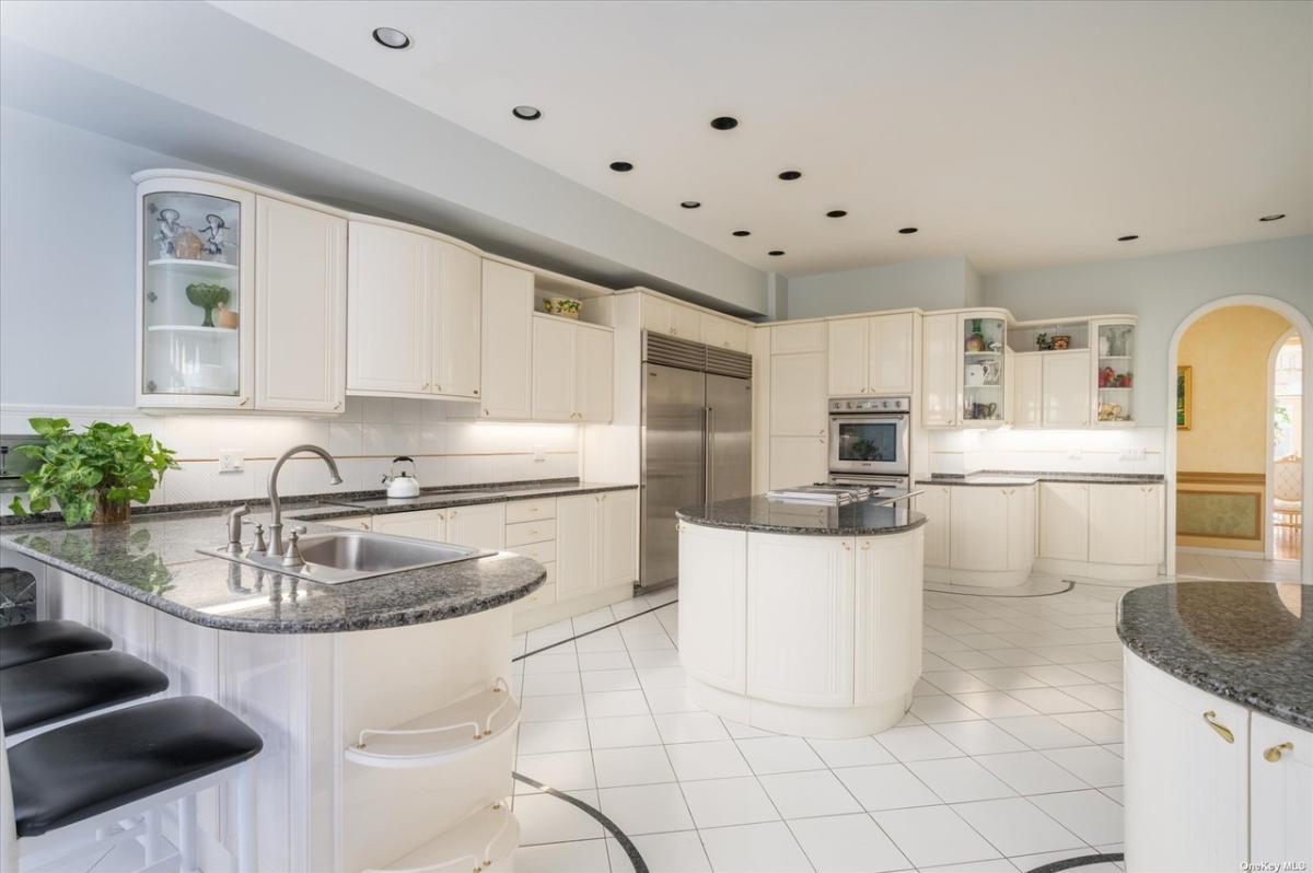 Kitchen with marble countertops, stainless-steel appliances and custom cabinetry.