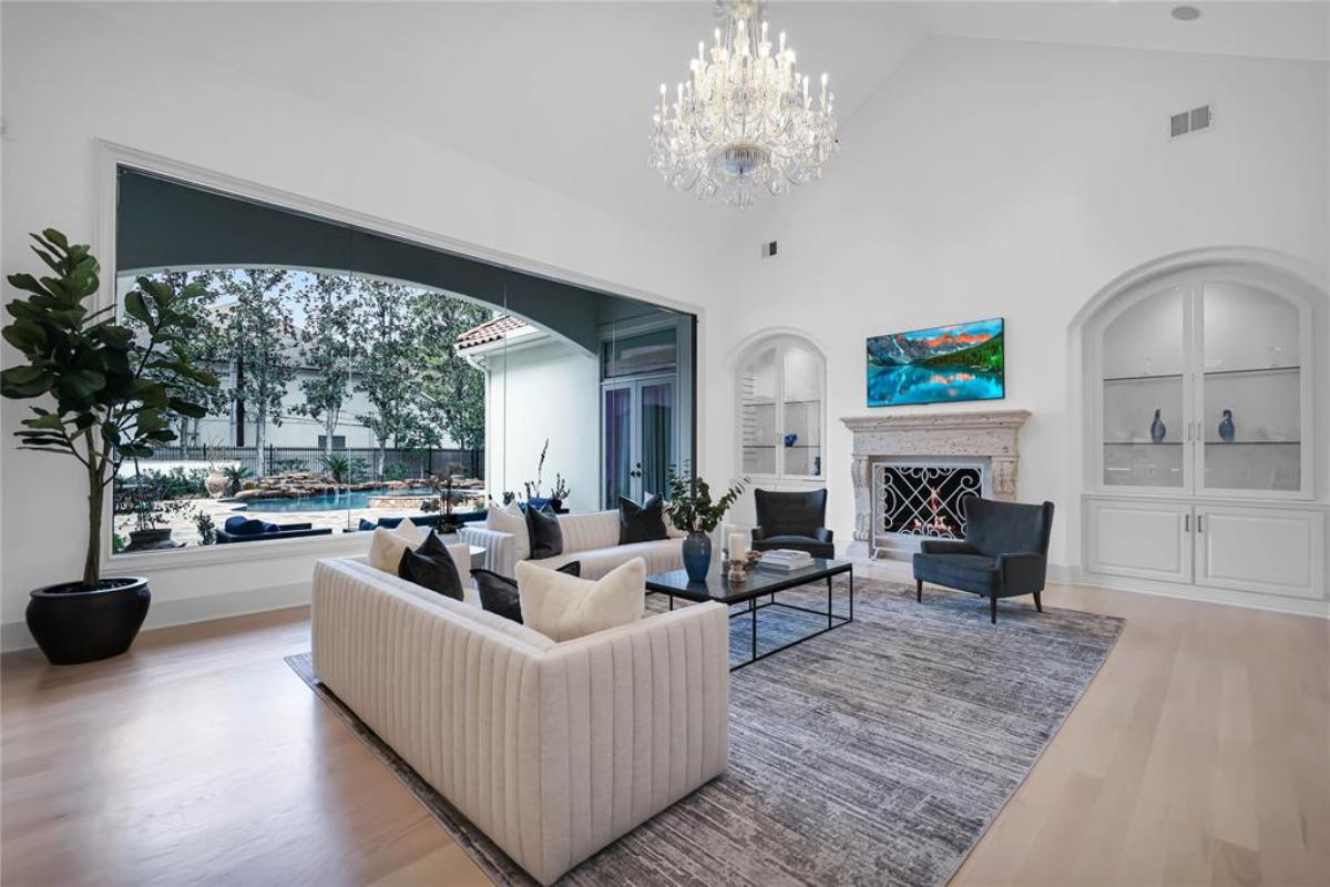 Living room with a chandelier, glass wall and a fireplace.