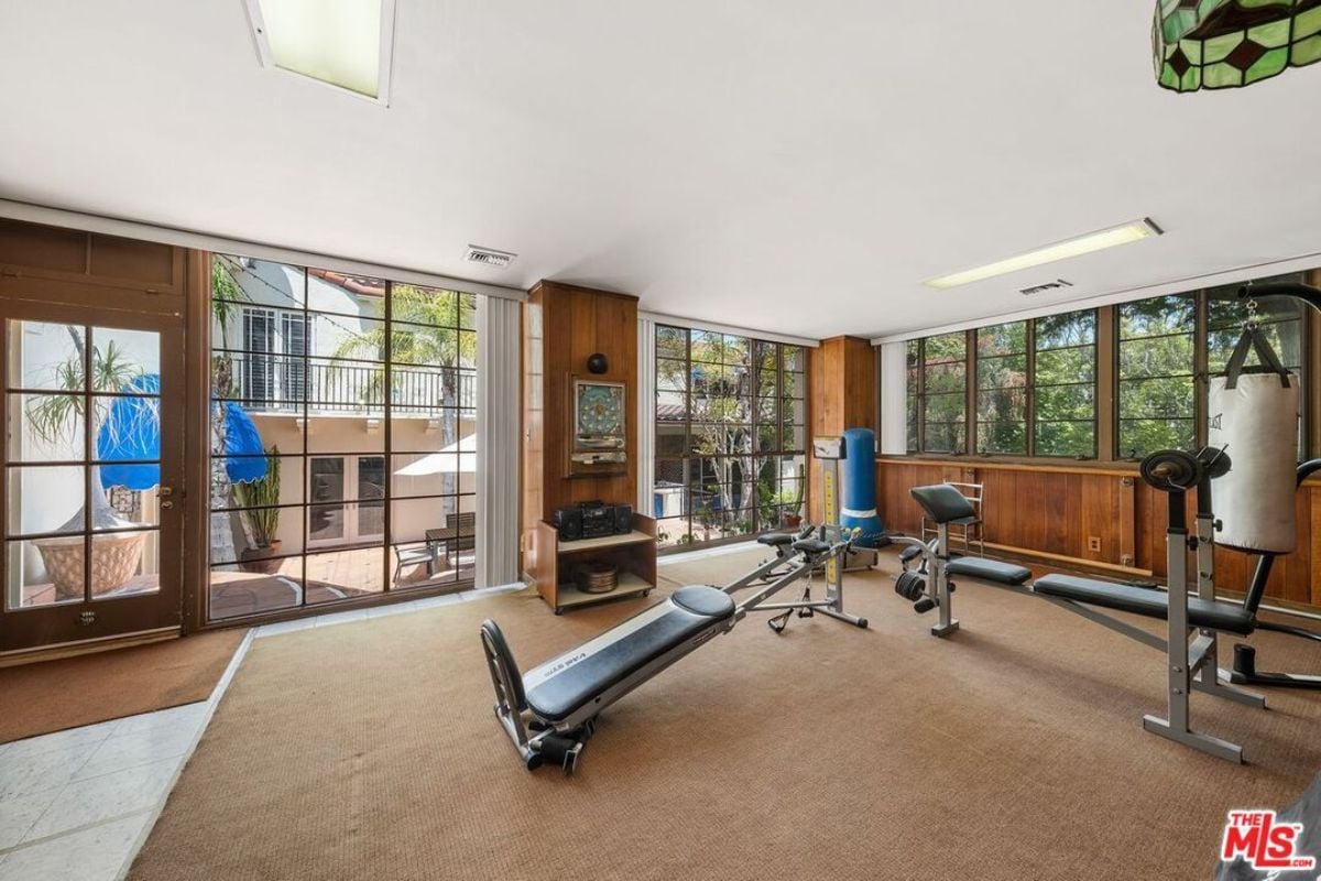A home gym with windows and gym equipment.