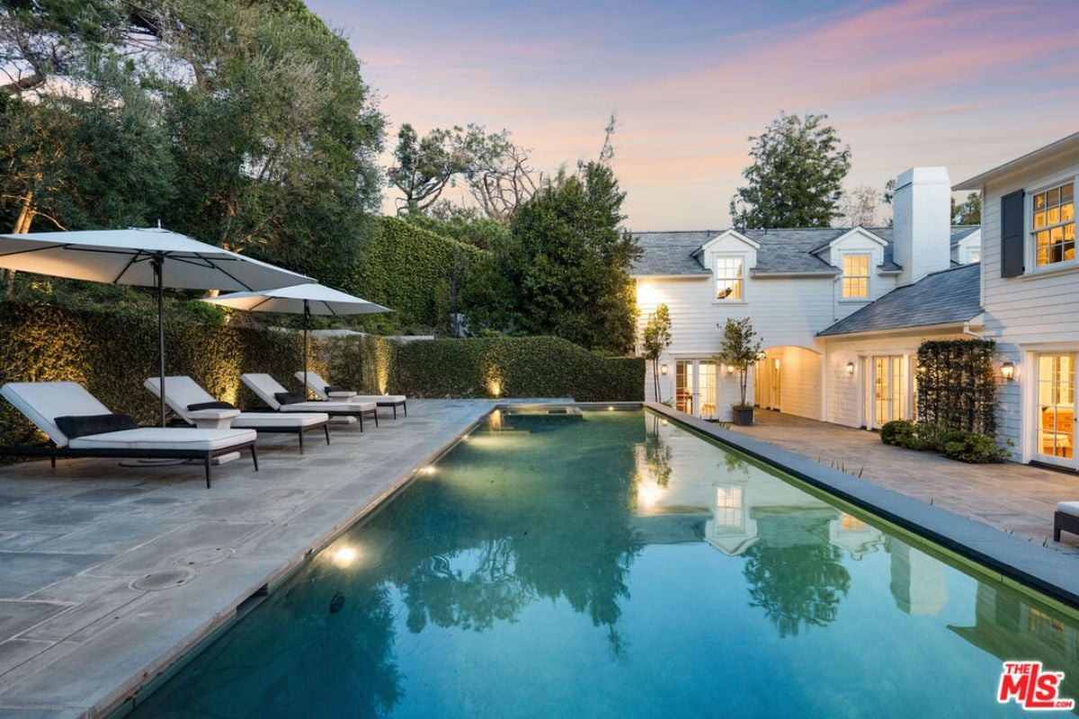 A swimming pool with chairs and umbrellas on the poolside.