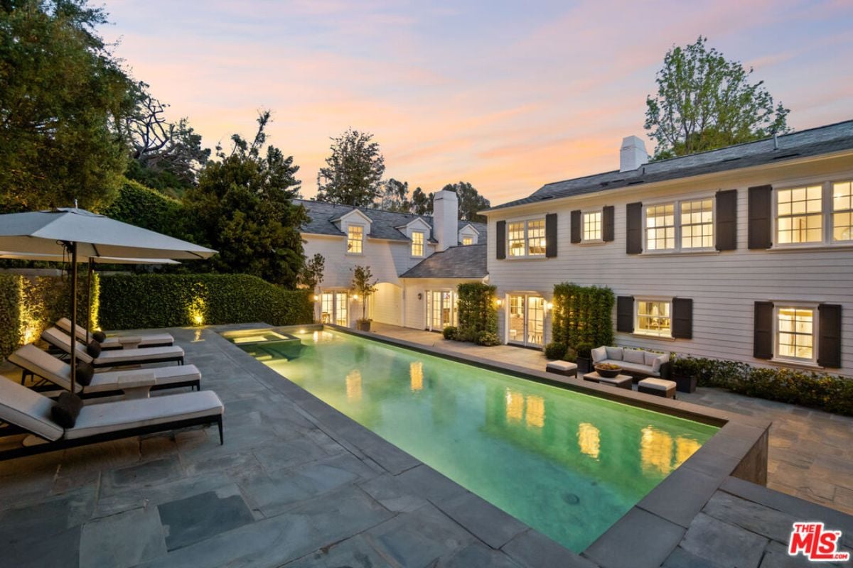 A swimming pool with chairs and umbrellas on the poolside.