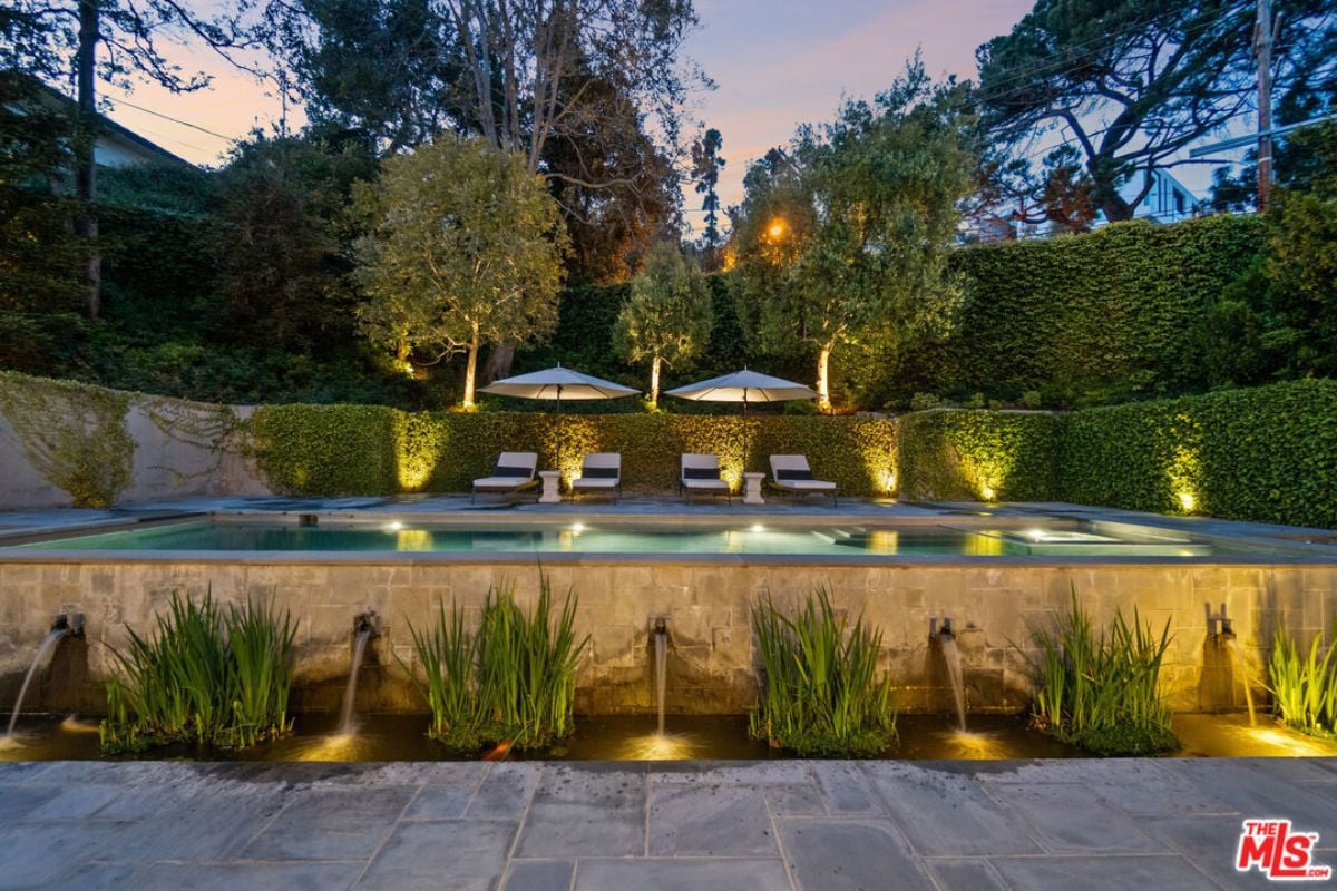 A swimming pool with chairs and umbrellas on the poolside.