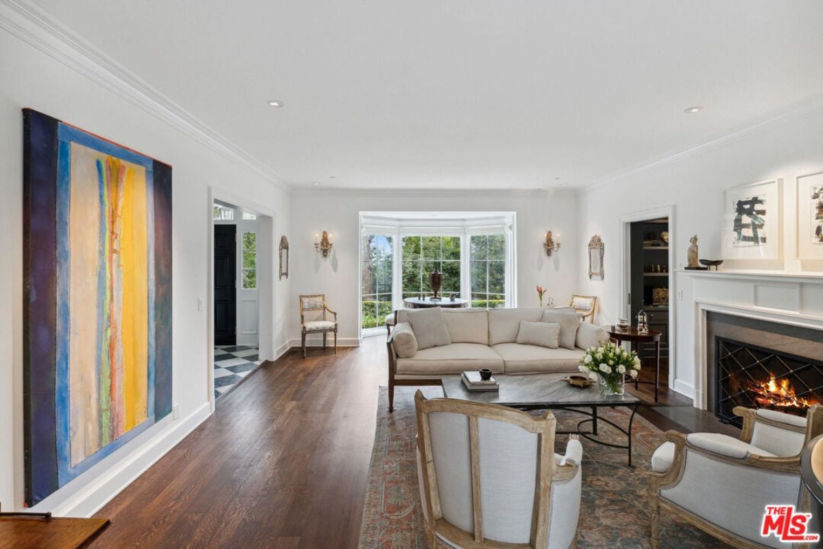 A living room with a fireplace, hardwood floor, rug, couch, chairs, center table, and a white ceiling.