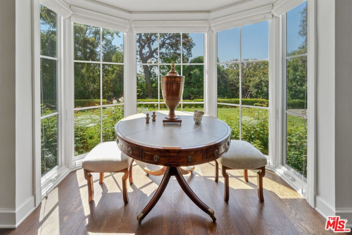 A breakfast nook with windows, a round table, and chairs.