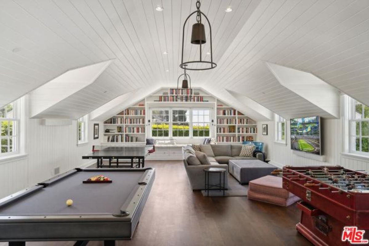 An entertainment room with shelves, a couch, TV, table tennis, and a pool table.