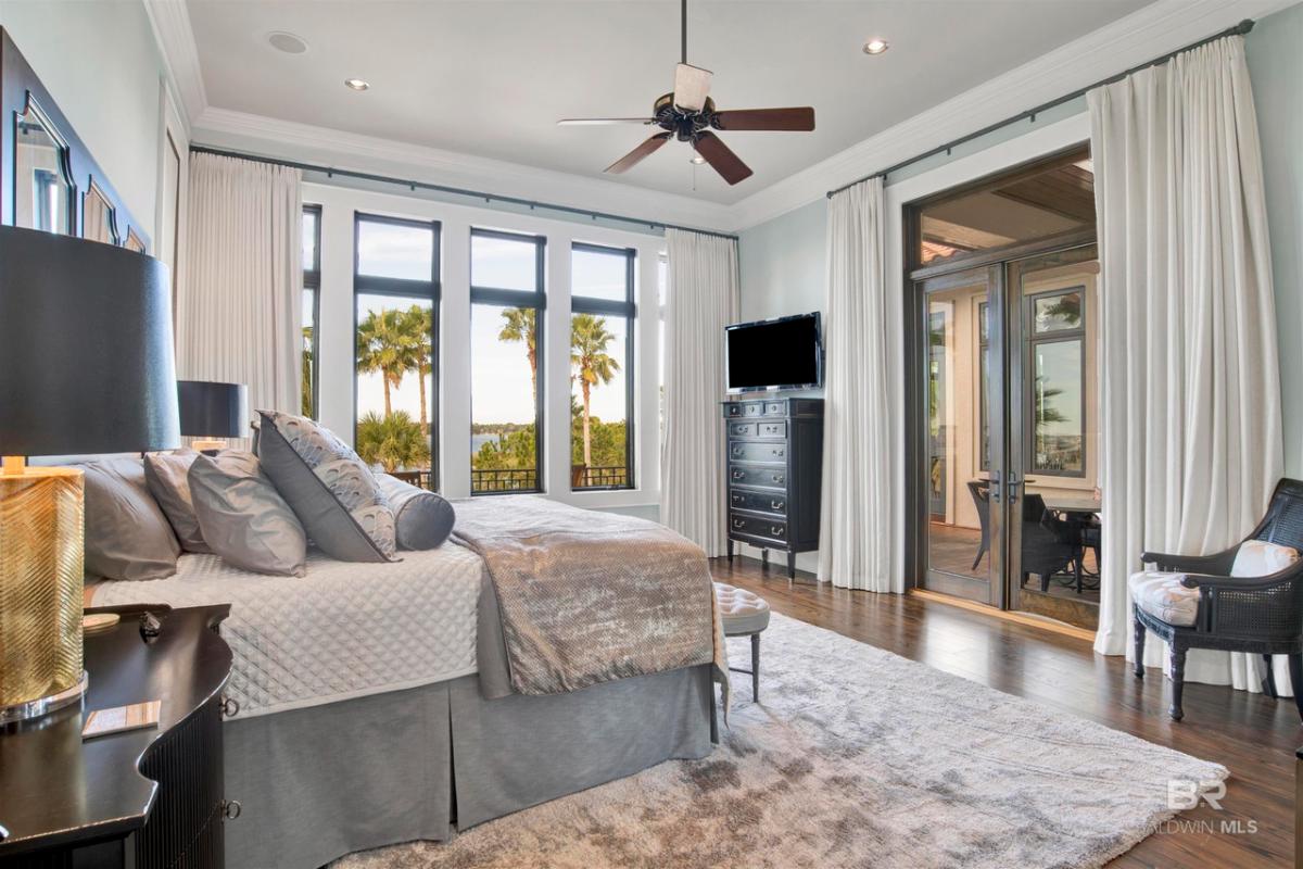 Bedroom with wood flooring, glass windows and glass doors.