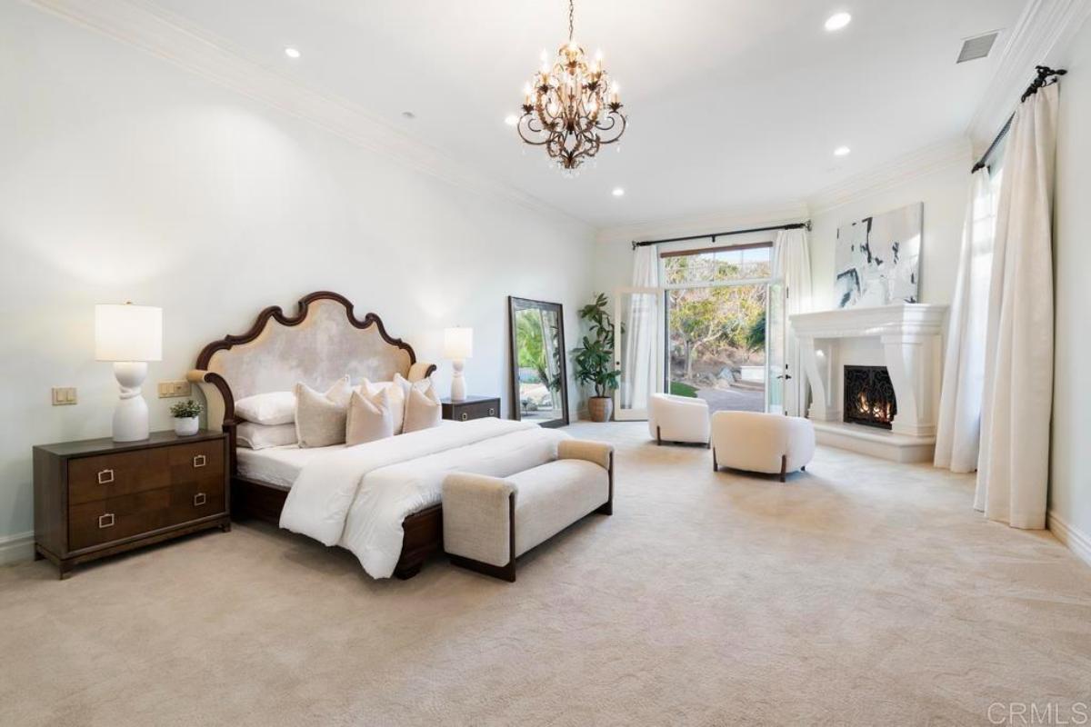 Bedroom with carpet flooring, chandelier and a fireplace.