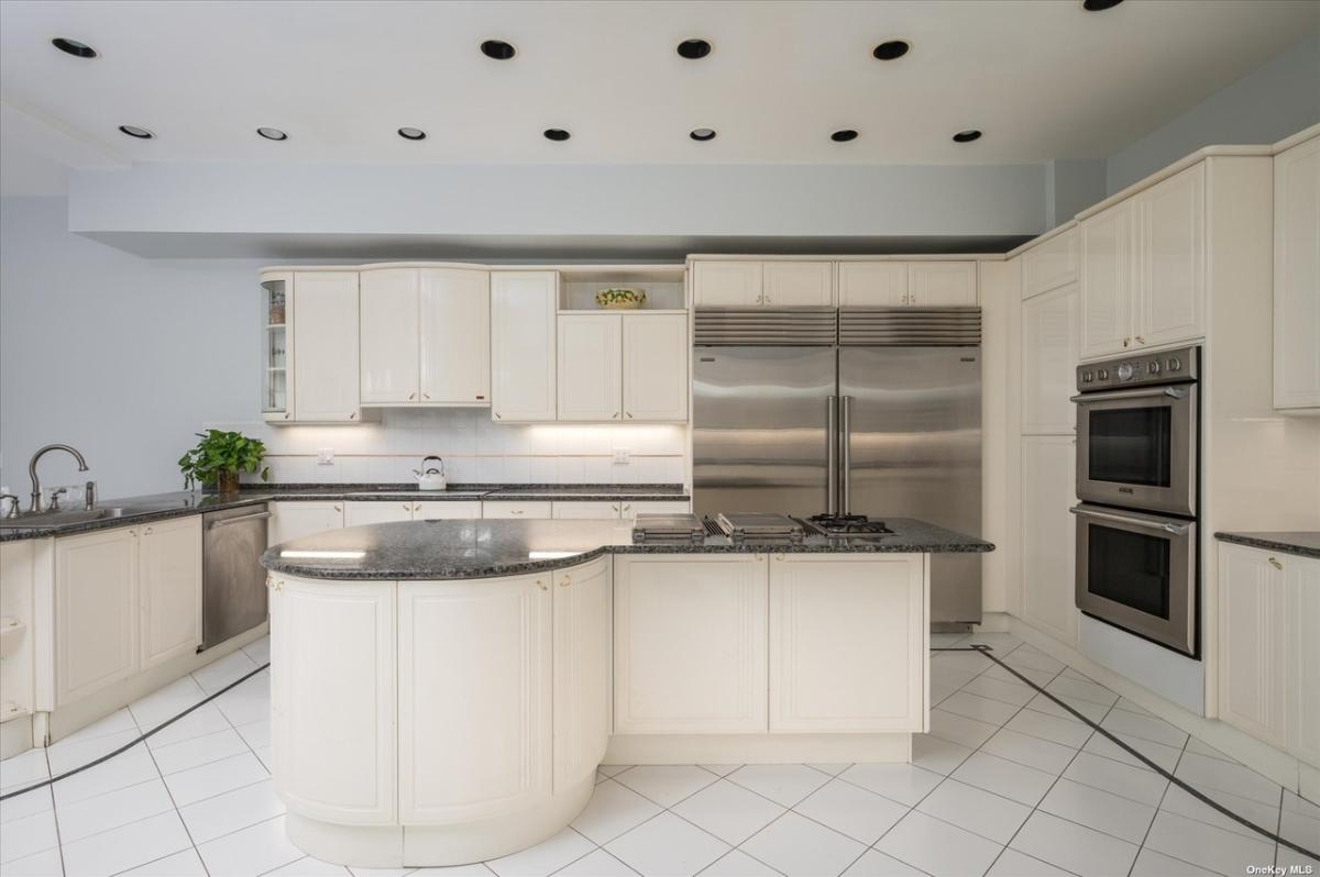 Kitchen with marble countertops, stainless-steel appliances and custom cabinetry.