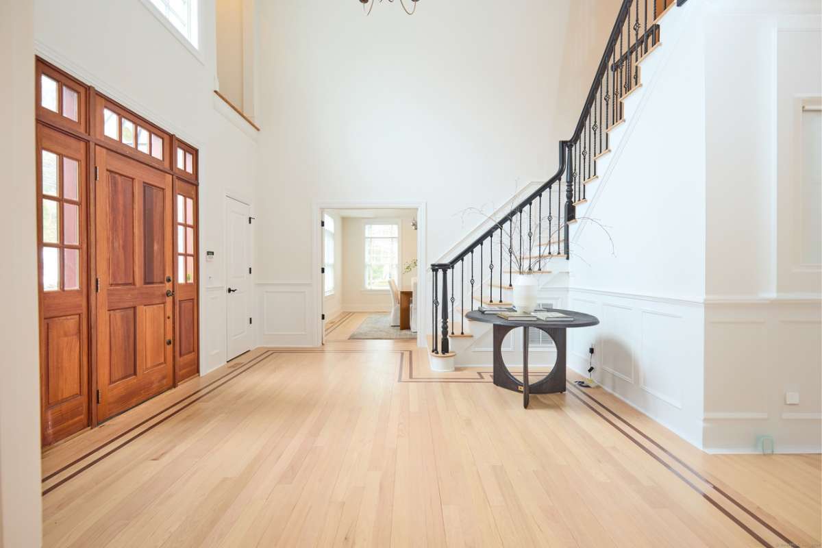 A foyer with a wooden floor, table, and staircase.