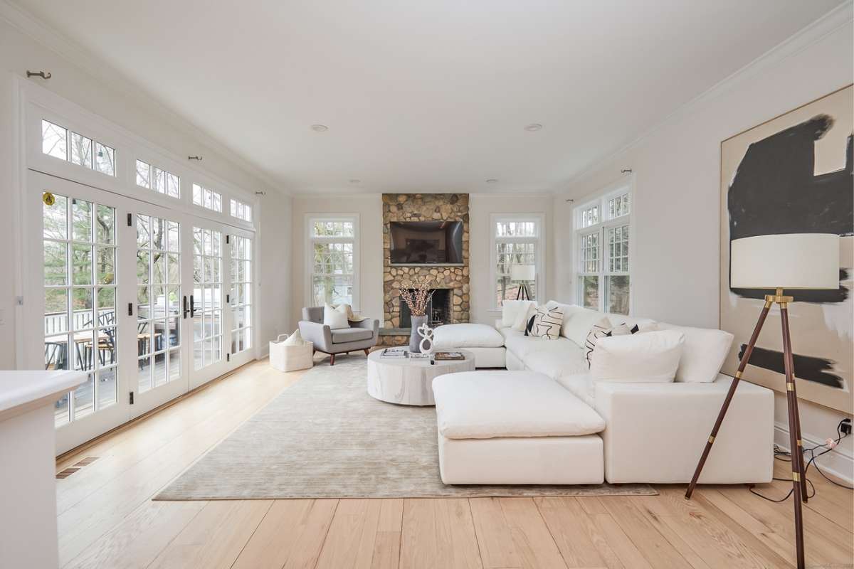 A living room with wooden floors, a rug, white couches, a fireplace, a coffee table, and a TV.