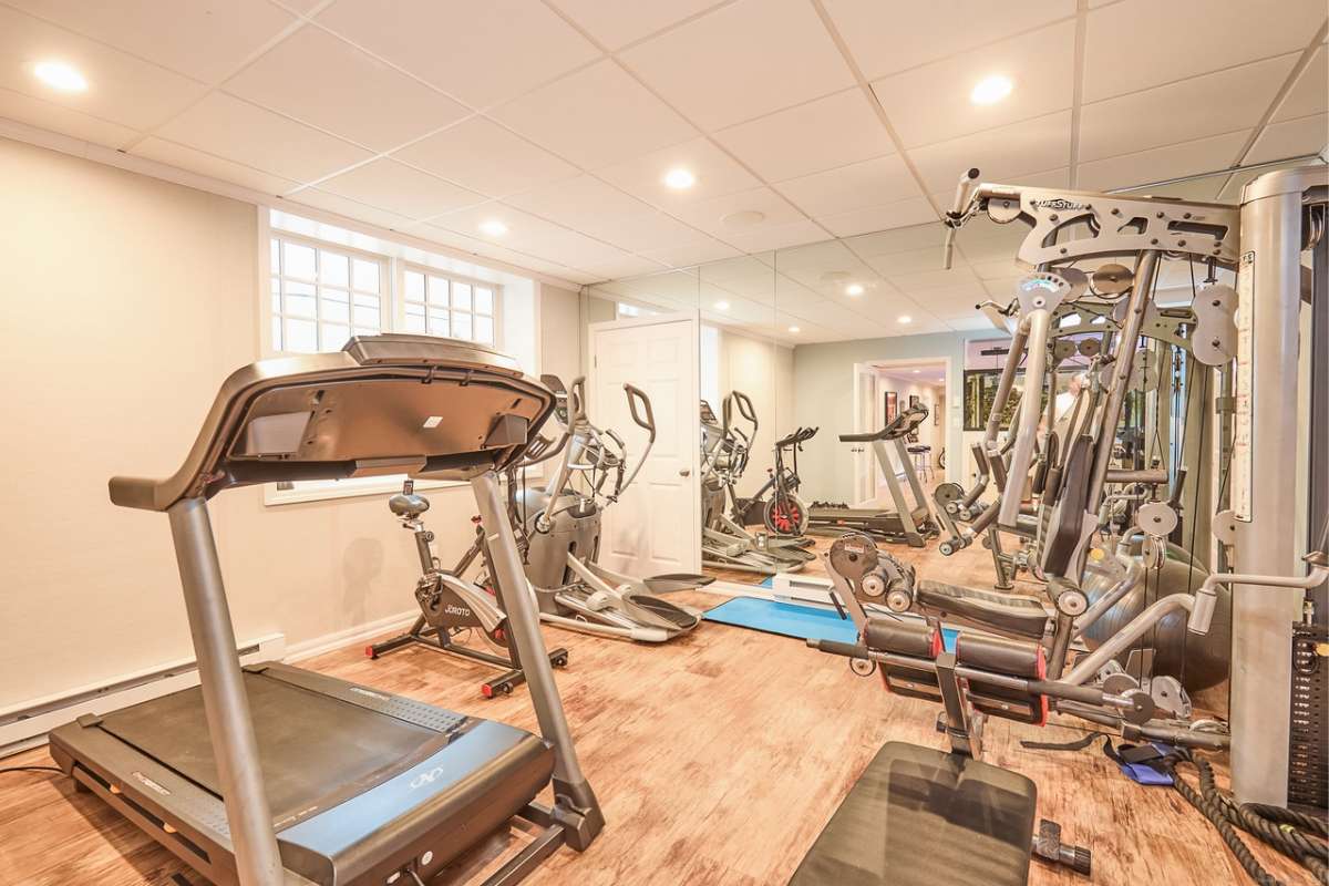 A home gym with a wooden floor, mirror, window, and gym equipment.