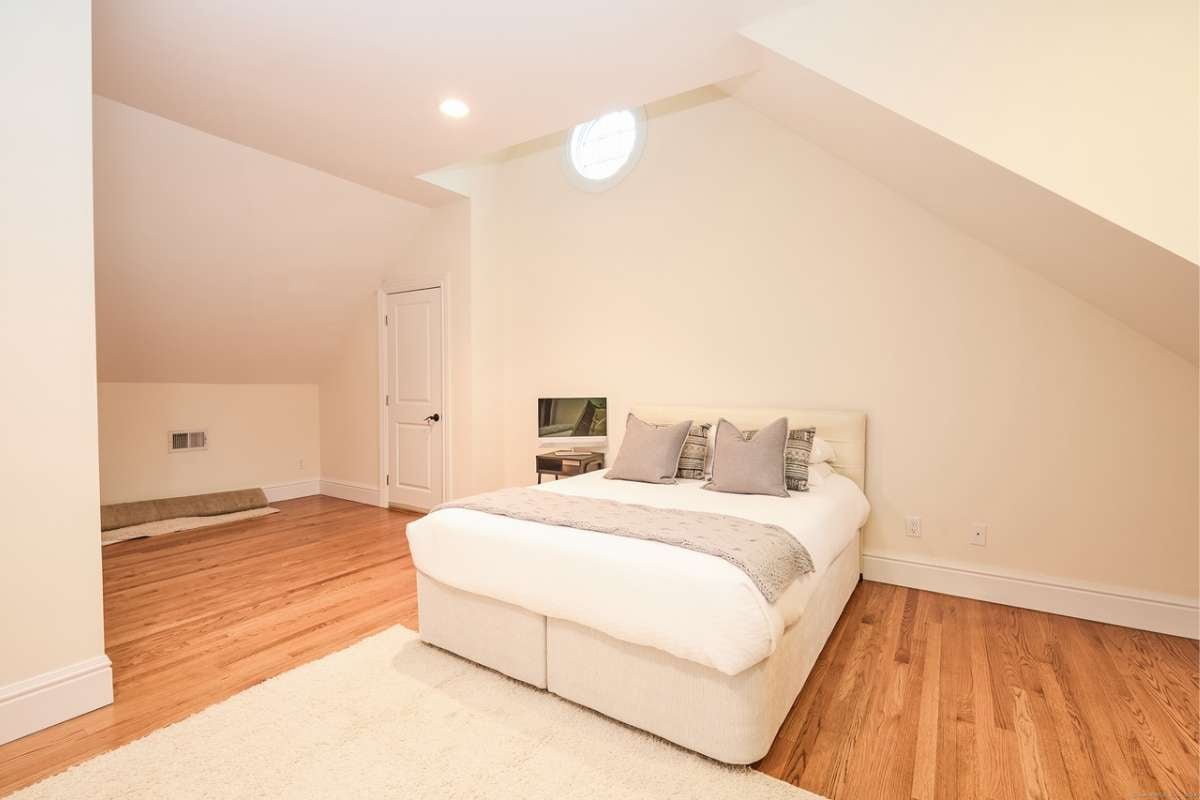 A bedroom with a bed, rug, wooden floor, and side table.