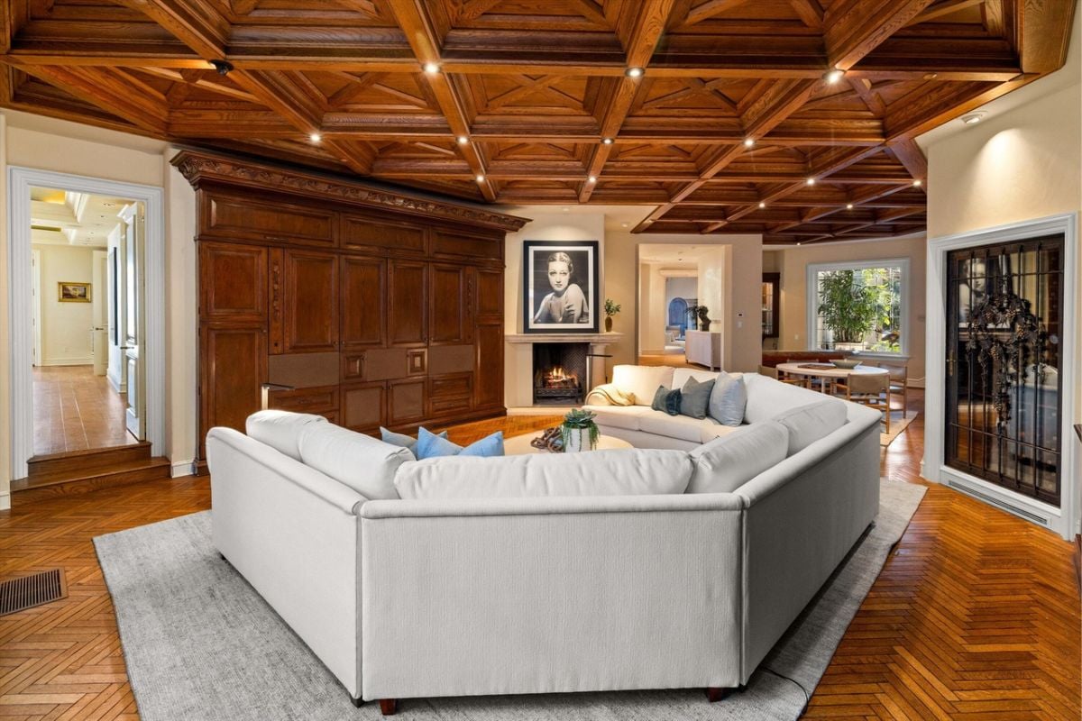 A living room with a fireplace and white couches with pillows.